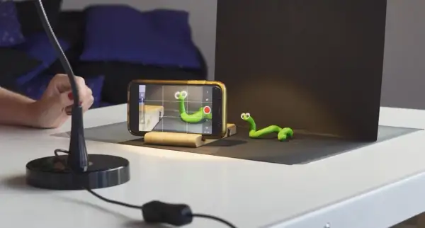 Tworzenie zielonych robaczków do animacji poklatkowej. Telefon nagrywa, ręka reguluje lampę.